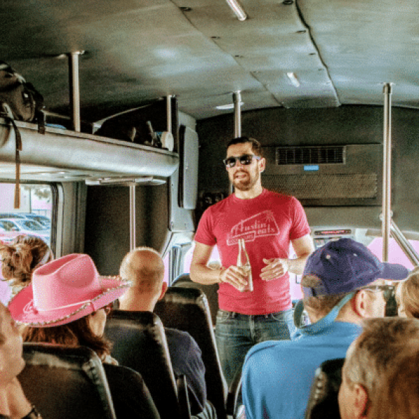 A man speaking to a group of participants on a bus during a food tour